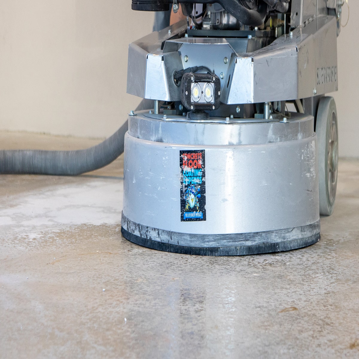 A large industrial-grade concrete flooring grinder sanding a concrete surface for epoxy resin installation.