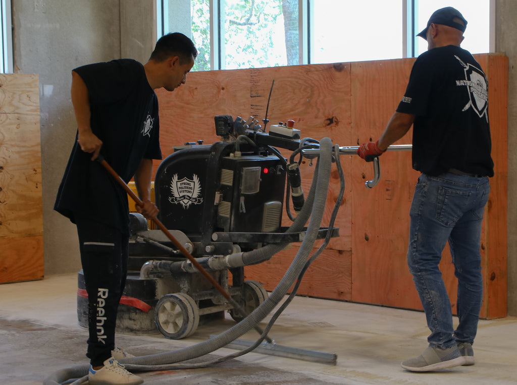 A contractor operating a floor grinder to get the best mechanical surface preparation out of concrete for an epoxy flooring installation.