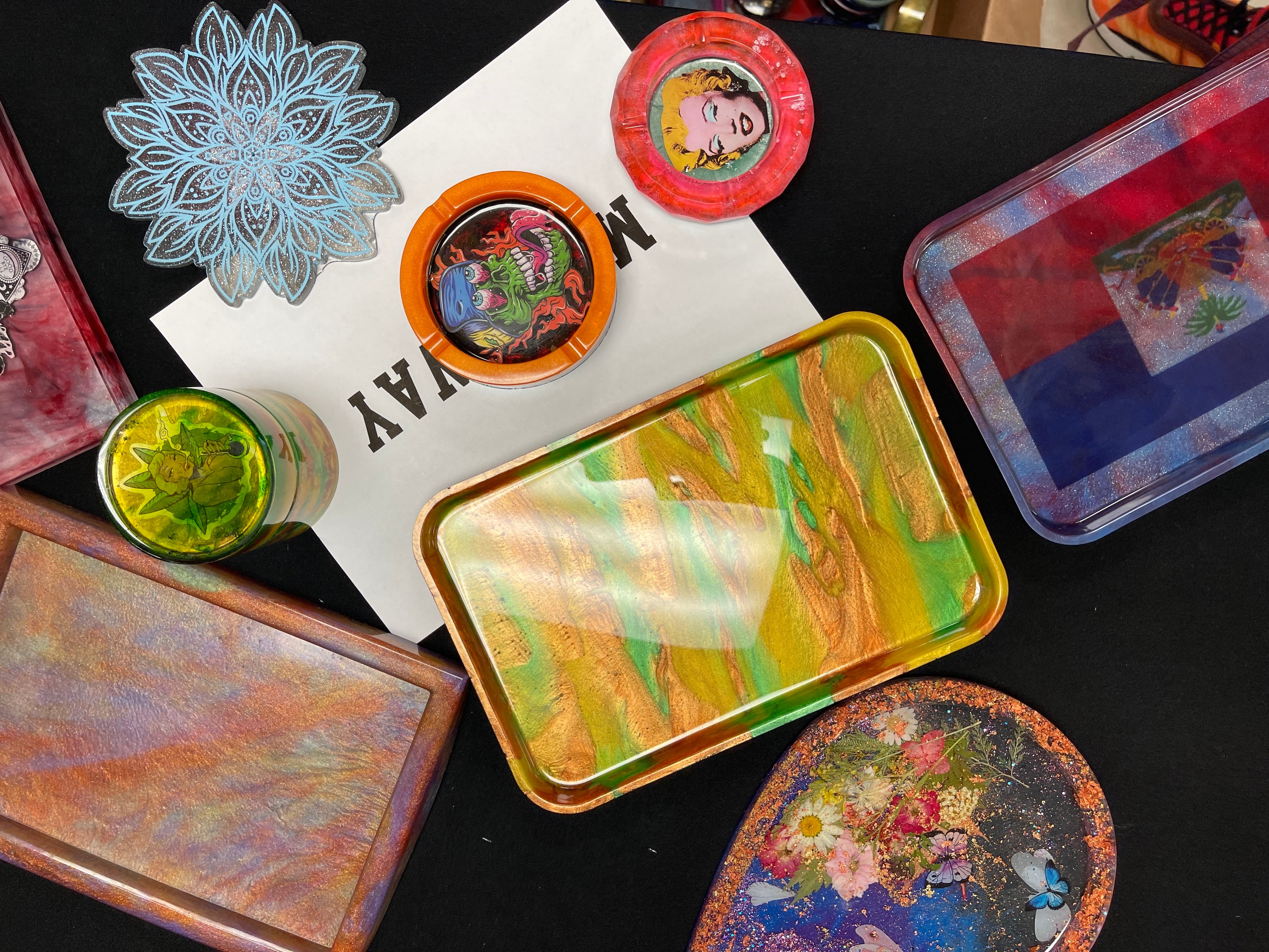 DIY epoxy resin crafts, such as epoxy ashtrays, spread out on a table.