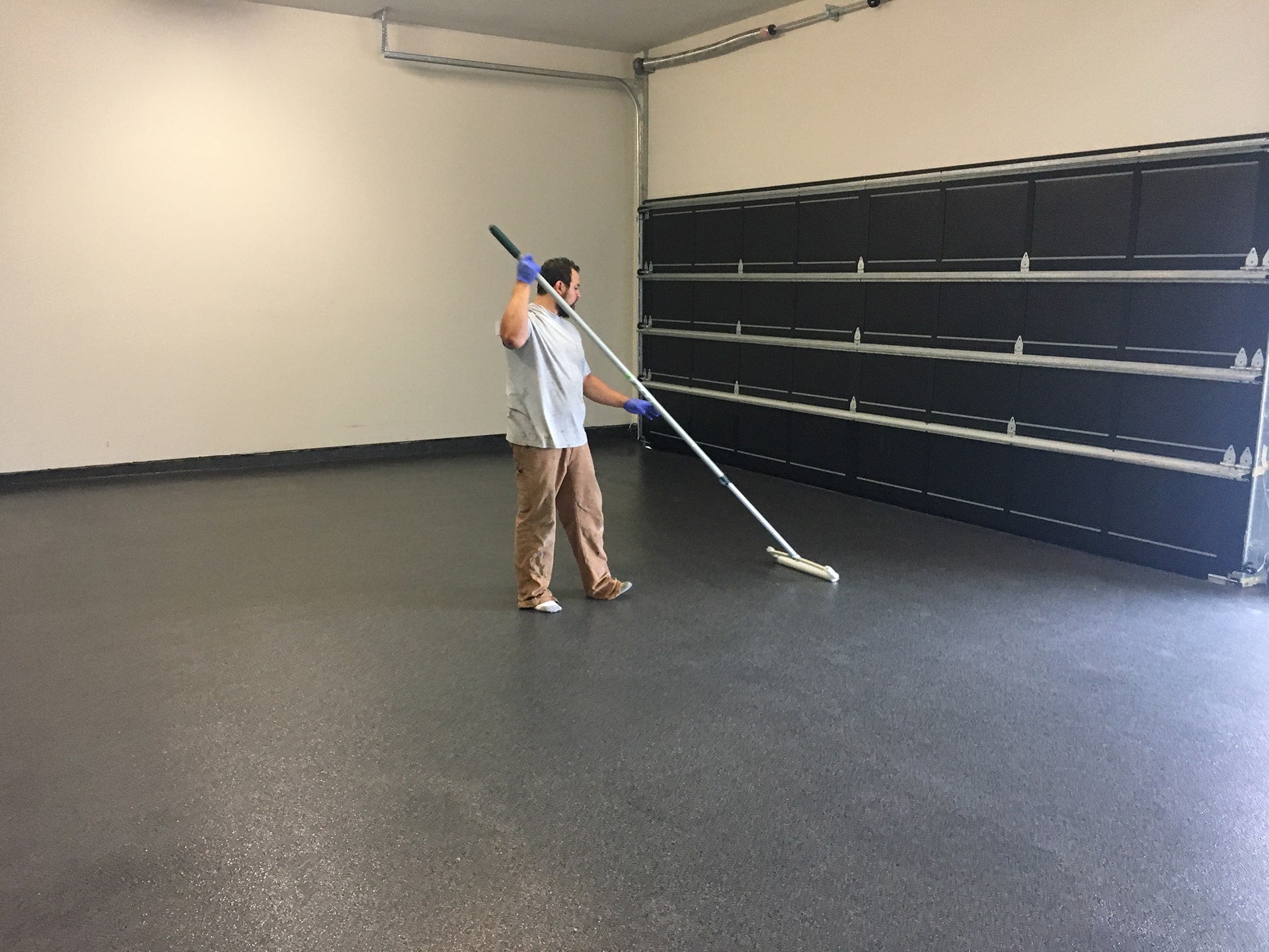 man with squeegee working on garage epoxy floor